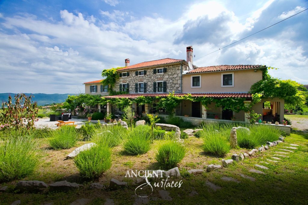 Stone faced hillside farmhouse with vine covered pergolas above a lavender garden edged in rough reclaimed limestone blocks